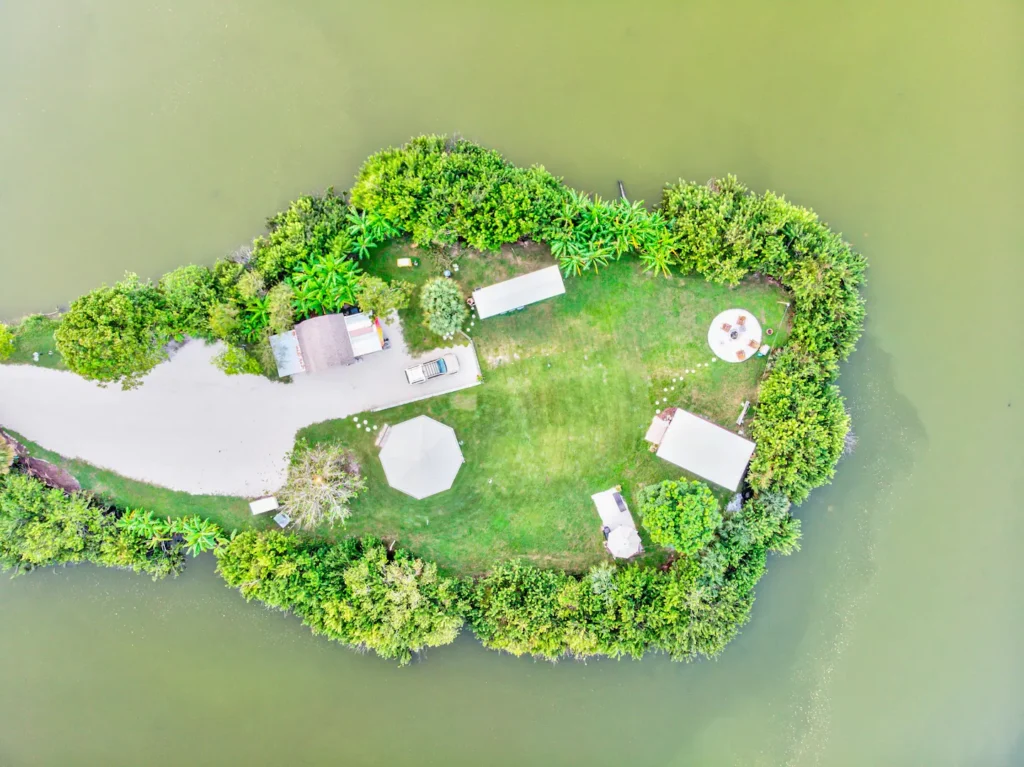 Drone photo of Shellmate Island, a private 1.5 acre island in Sarasota, Florida, surrounded by water, with two tiny houses, a lawn and tropical trees