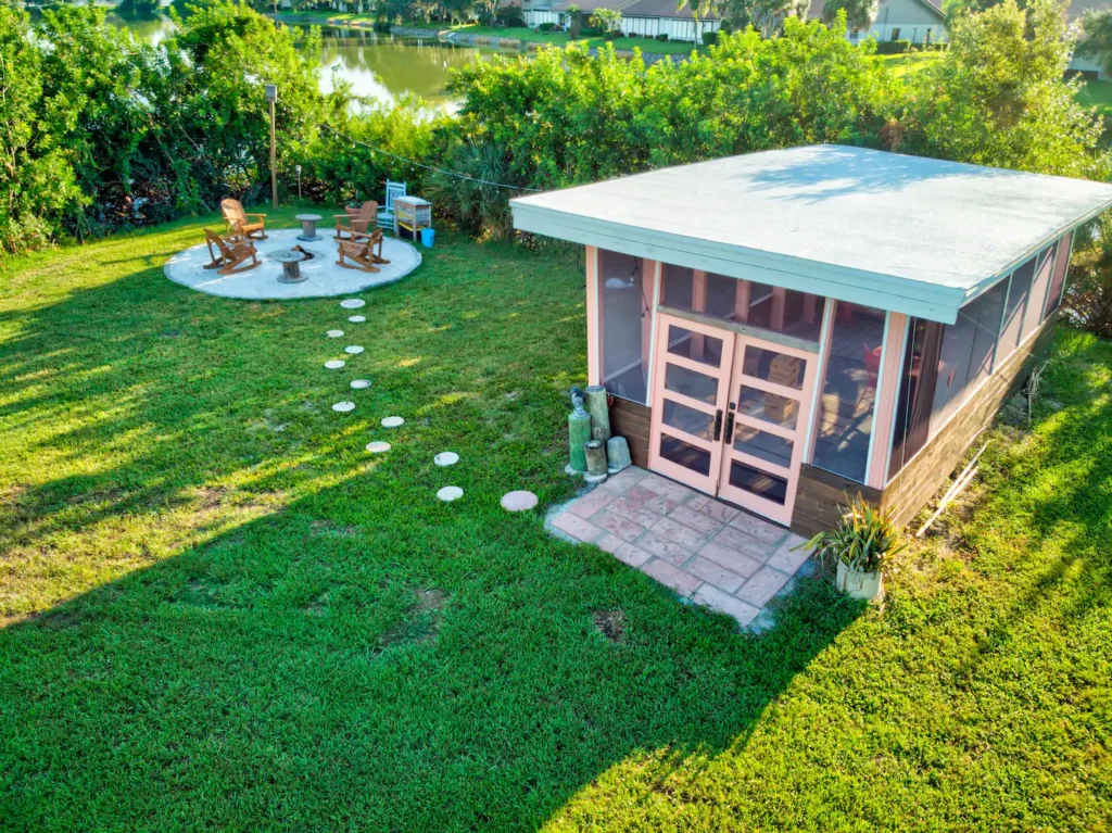 Aerial view of the screened lounge building and the fire pit with Adirondack chairs on Shellmate Island, connected by stepping stones across the lawn