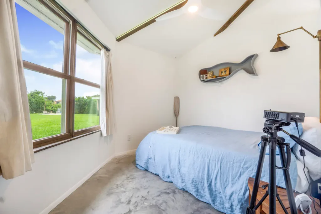 Bedroom in Stanley on Shellmate Island with a large window looking out over the lawn and water, white walls and a queen bed