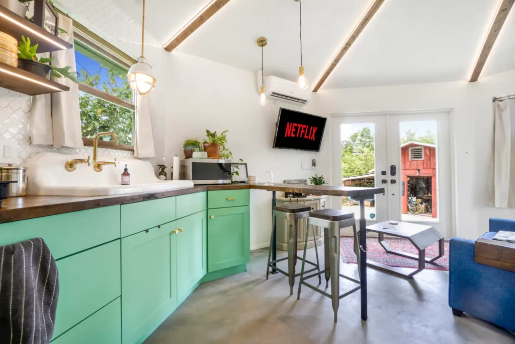 Kitchen in Stanley on Shellmate Island with mint-green cabinets, wood countertops, a bar with stools, a smart TV, and French doors with red trim opening to the lawn