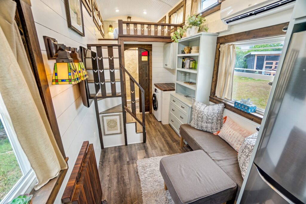Interior of Tiffany The Tiny Home showing the wood-trimmed living area, kitchen, and sleeping loft with ladder