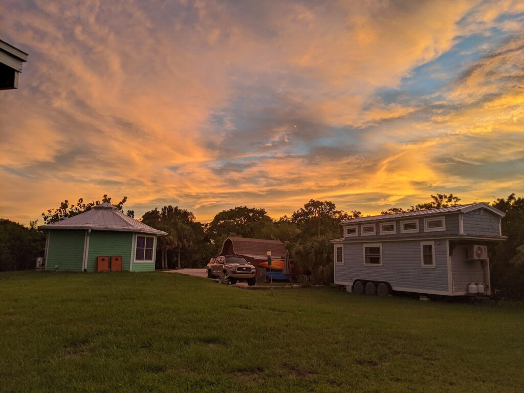 Two tiny home rentals on a private island near Sarasota at sunset: the mint-green octagonal Shellmate Island on the left and Tiffany The Tiny Home on the right