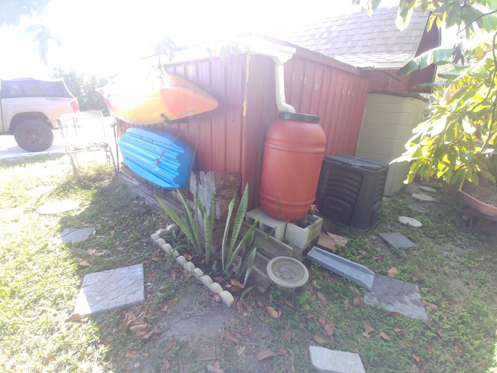Blue and orange kayaks stored on a rack beside a red shed on Shellmate Island, free for guests to use